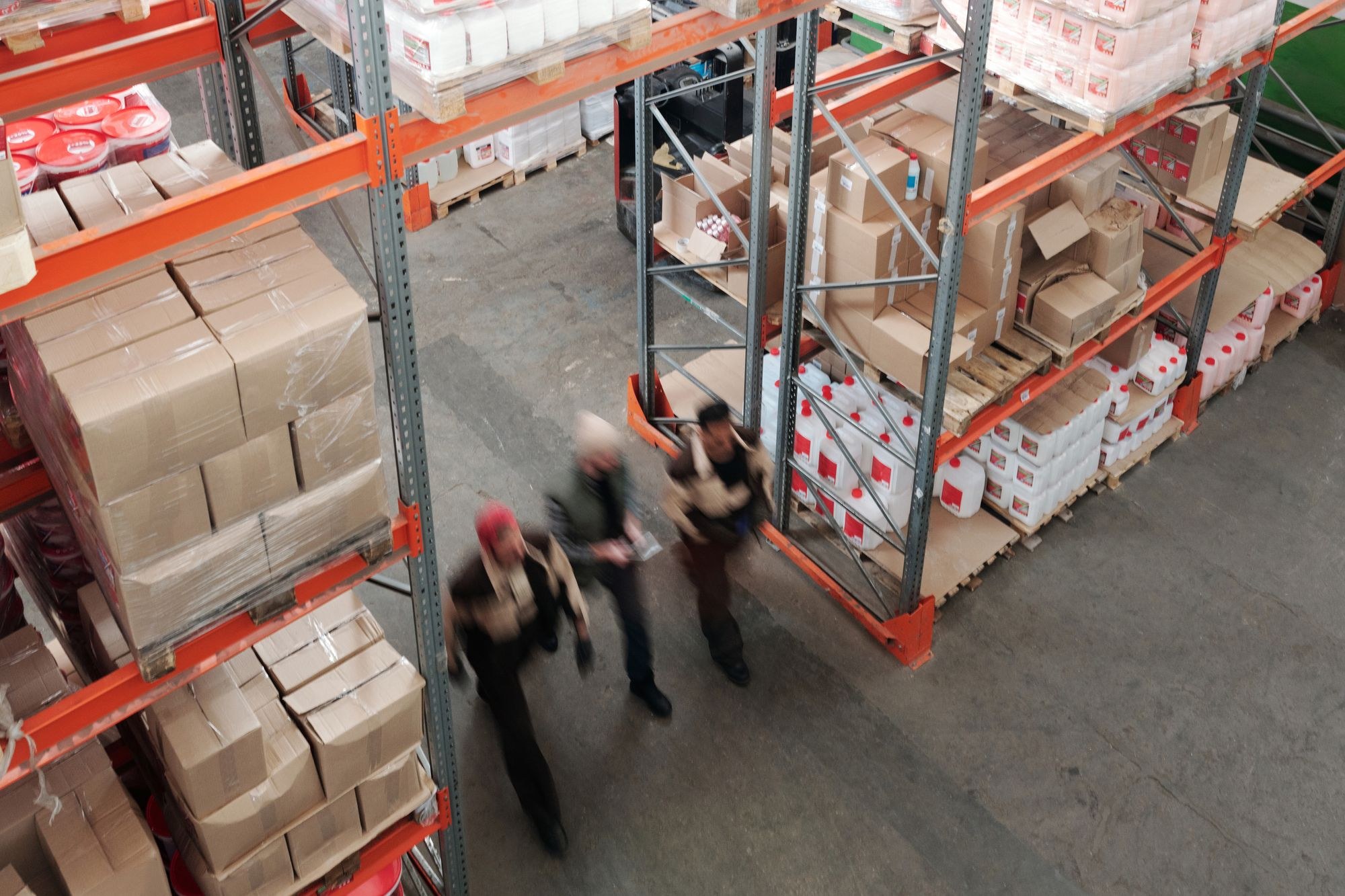 Overhead view of a stocked warehouse with employees walking between racks